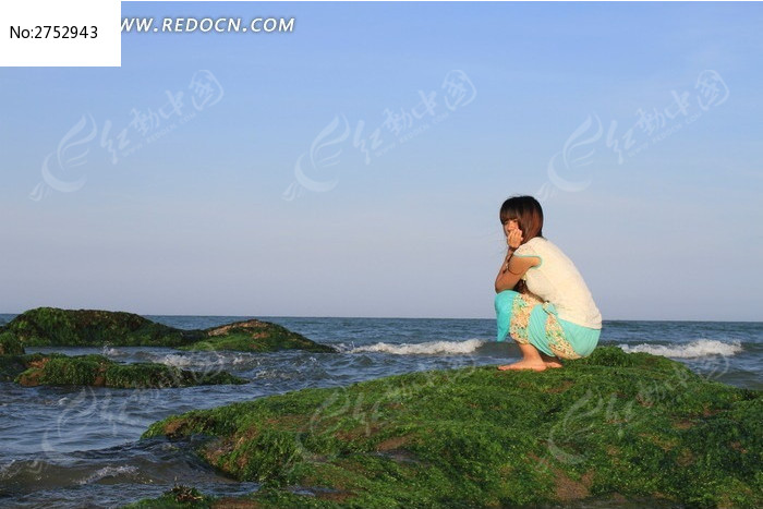 站在海边石头上沉思的女生