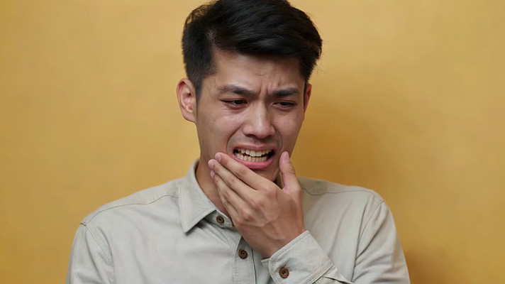 男性捂嘴表情痛苦