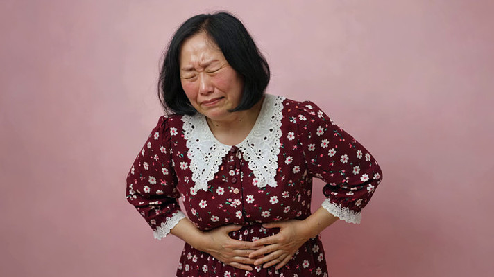 女性捂着肚子面露痛苦