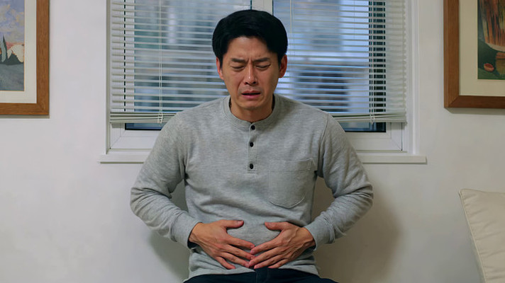 男性双手扶腹面露痛苦