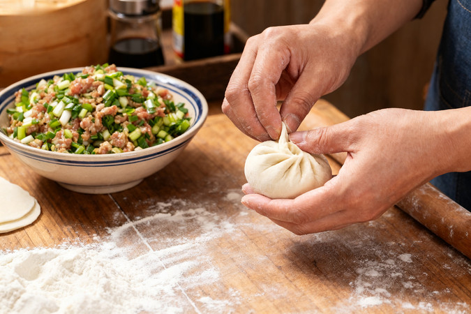 双手捏制包子桌上有馅料和面粉 双手捏制包子桌上有馅料和面粉