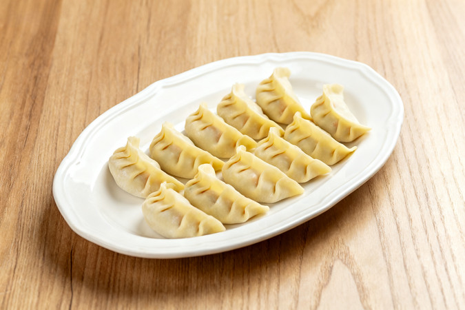 白色盘子里整齐摆放的黄色饺子 白色盘子里整齐摆放的黄色饺子