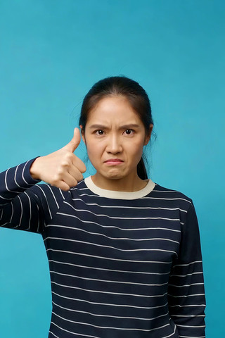 女子蓝色背景下竖大拇指 女子蓝色背景下竖大拇指