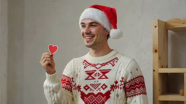 戴圣诞帽男子手持爱心卡片 戴圣诞帽男子手持爱心卡片
