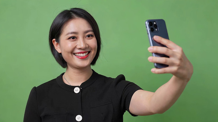 女性绿幕前手持手机自拍 女性绿幕前手持手机自拍