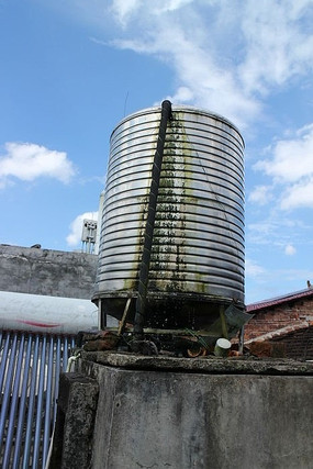 屋顶上长着青苔的不锈钢储水塔